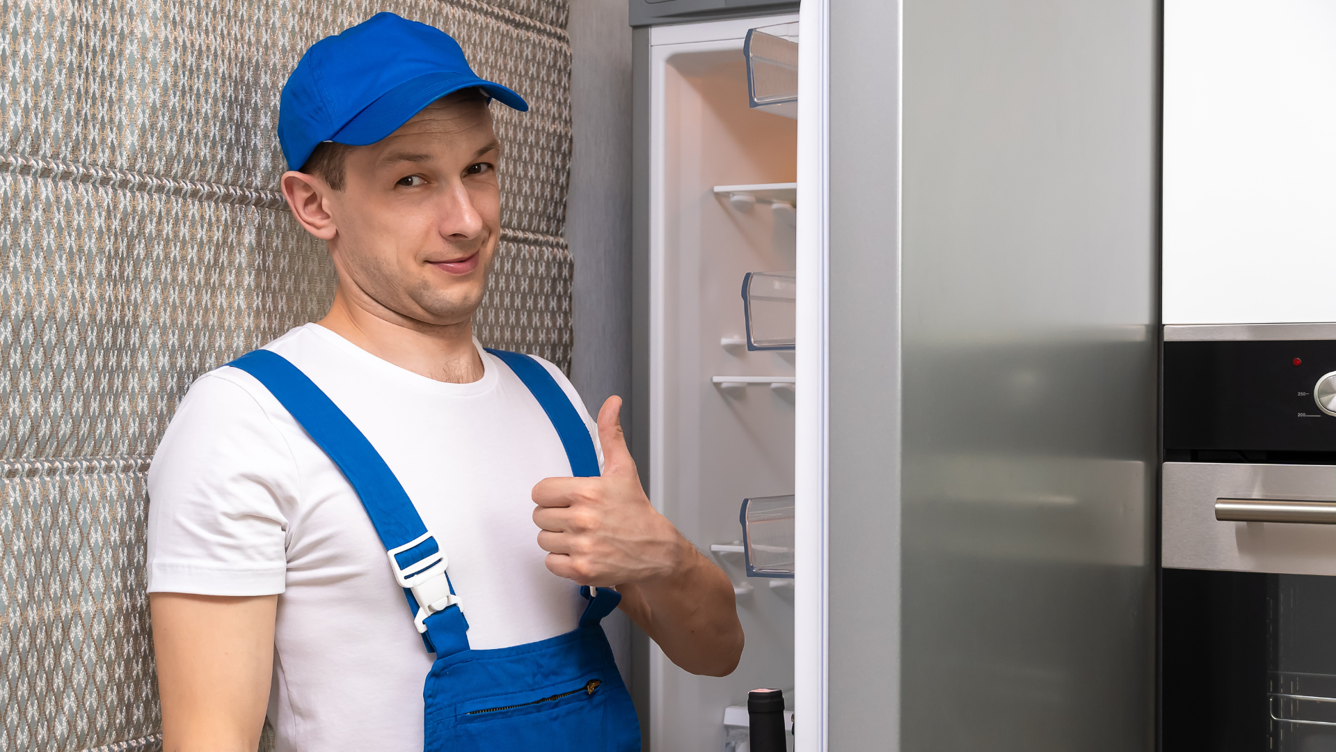 Installatore professionista di cucine sorride con pollice in su davanti a un frigorifero